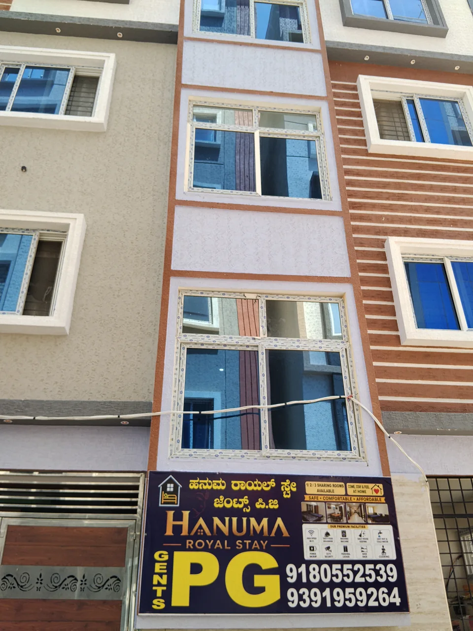 Front of Hanuma Royal Stay Gents PG, showing its cream and terracotta facade, windows and entrance sign.